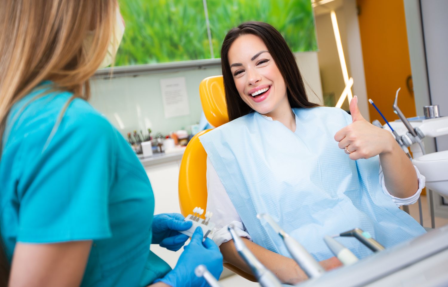 Portrait of beautiful young smiling woman visiting dentist giving thumbs up