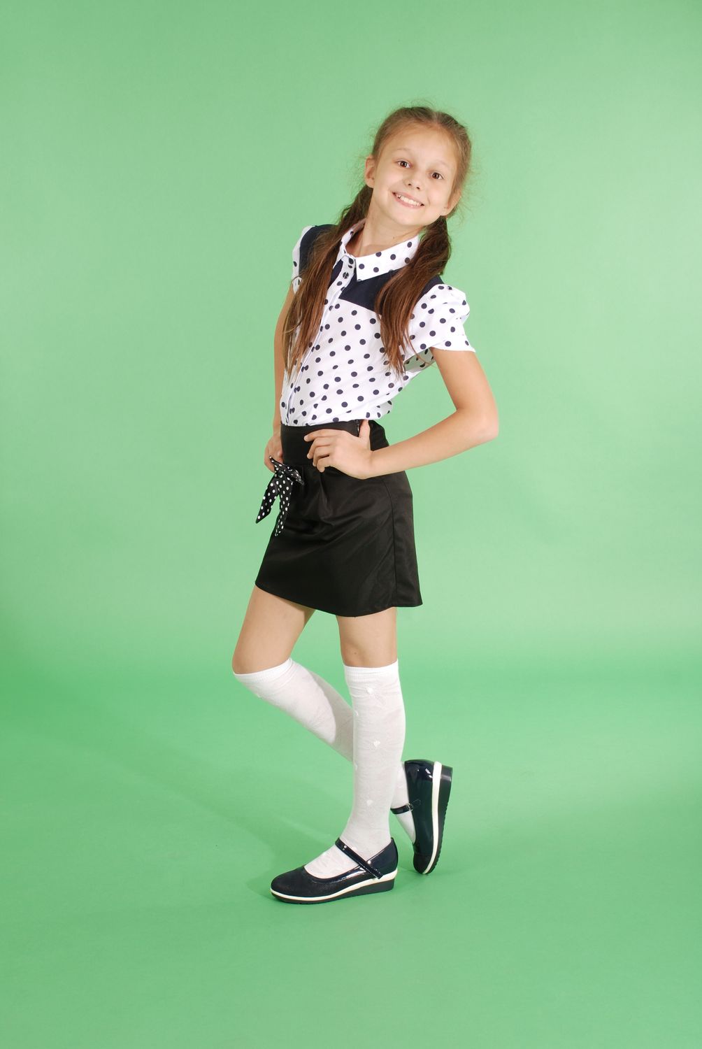Beautiful young girl in school uniform isolated on green