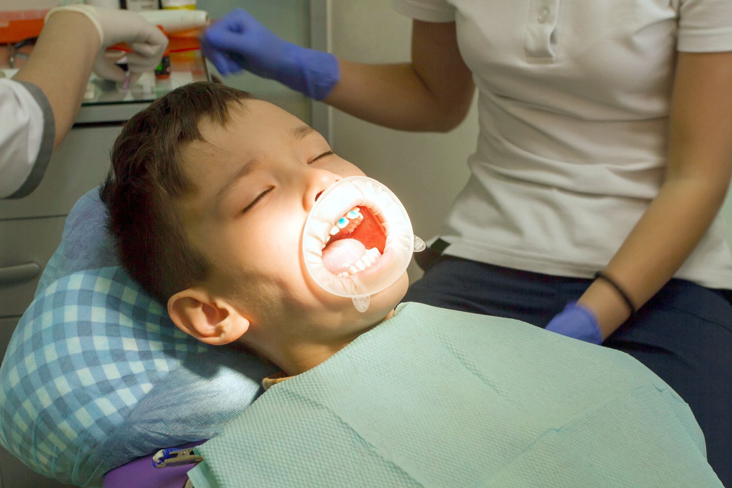 Orthodontist examining boy mouth. Orthodontist put braces on teeth. Boy afraid of dentist