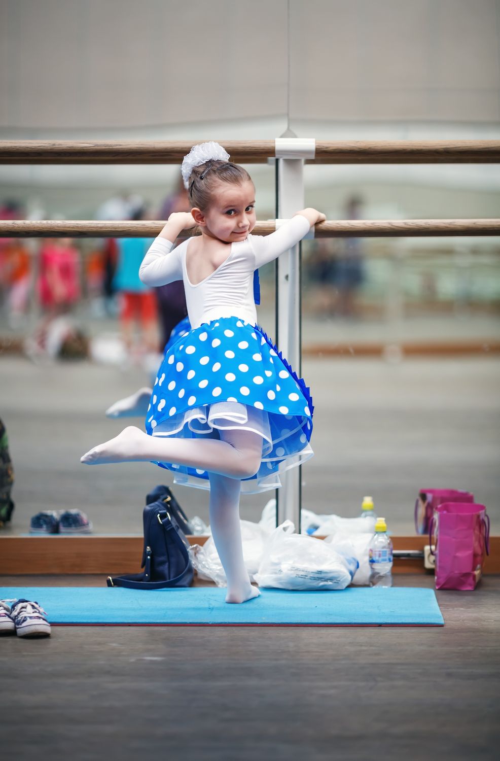 Little ballerina practicing in a dance class. Child girl posing at ballet barre in a dance class. Preschool child taking dance lessons. Ballet school. Shallow depth of field. Selective focus.